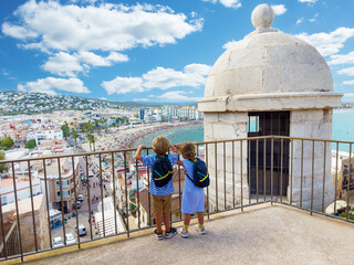 Fototapeta na wymiar Two travelers enjoy view from Peniscola castle high viewpoint