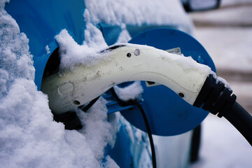 Electric car charging station covered with snow in winter. Close up.
