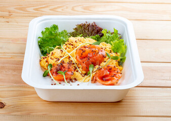 Salmon scramble. Healthy food. Takeaway food.  On a wooden background.