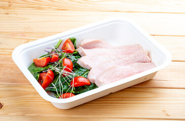 Turkey sous-vide with vegetables. Healthy food. Takeaway food.  On a wooden background.