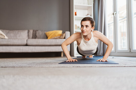 Empowered Young Woman Doing Push-Ups with Determination in Her Living Room