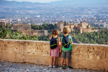 Cute boy and girl overlook magnificent castle Alhambra, Spain