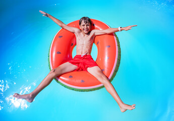 Young swimmer relax on big inflatable ring, in star shape pose - obrazy, fototapety, plakaty