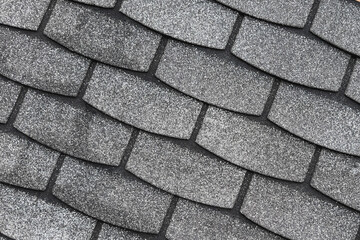 Gray bitumen shingles laid diagonally. Modern roofing materials.