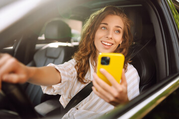 A woman driver  with phone. Woman texting on smartphone while driving car. Checking email chats and...