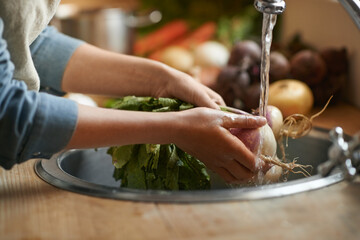 Hands, sink and water to clean vegetables in kitchen, health and hygiene with chef cooking food and...