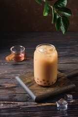 Cool drink, Taiwanese bubble tea with almond milk with tapioca balls in a glass glass on a dark wooden background. Refreshing soft drinks, cocktails.