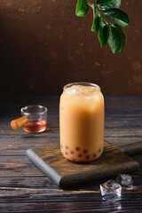 Cool drink, Taiwanese bubble tea with almond milk with tapioca balls in a glass glass on a dark wooden background. Refreshing soft drinks, cocktails.