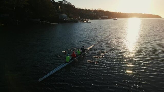 Cinematic shot of the throne group of sport canoes driven by young athletes training at sunrise in an ocean bay, Halifax, Canada.Rowing club practicing in the ocean bay at sunrise early in the morning