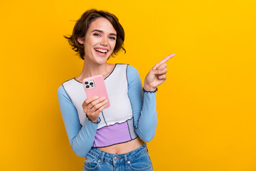 Photo of adorable pretty woman wear top typing apple iphone samsung device pointing empty space isolated yellow color background - obrazy, fototapety, plakaty