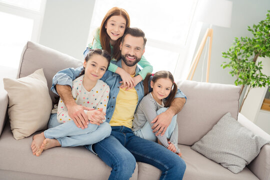 Photo of four persons sit on couch guy hugging girls toothy smile enjoy free time weekend hone indoors
