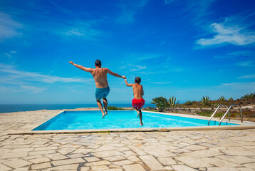 Family fun of father and kid with a poolside jump at resort