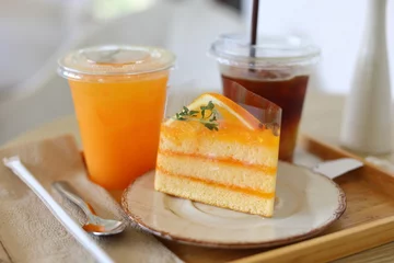 Poster Delicious orange cakes with orange juice are placed on a wooden table in a cafe. Dessert concept. food © SUPERMAO