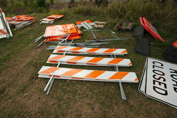 Multiple orange and black detour ahead signs barricades and orange cones in a  grass field. Also...