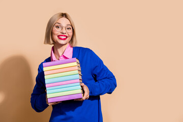 Photo of charming excited person beaming smile hold pile stack book empty space isolated on beige color background