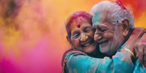 Elderly Indian couple hugging against colorful background. Holi color festival banner with copy space
