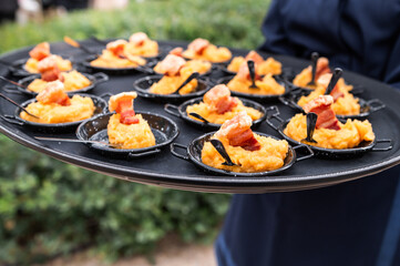 A waiter serving a plate full of pork cracklings at an event.