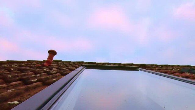 Dachfenster mit sich spiegelnden Wolken die Abends im Zeitraffer vorbeiziehen, rote Ziegel, Dachdämmung
