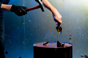 close-up hand smashes a glass bottle with a hammer attack robbery crimes thief danger performance