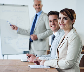 Fototapeta premium Portrait or business people or boss teaching in a meeting for presentation, coaching or team training. Smile, man or woman in boardroom meeting for skills, group learning or education in a mentorship