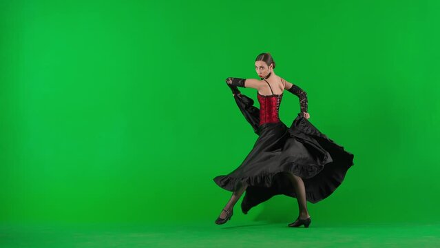 Woman dancer dancing on chroma key green screen. Female in flamenco style dress performs elegant spanish dance moves with her hands and body in the studio.