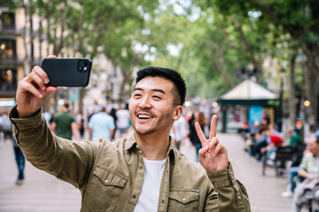 Man Making Peace Sign While Taking a Selfie in Urban Park