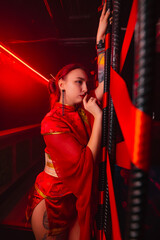 A beautiful girl in a kimono stands near red ribbons. The image of a geisha, Chinese national costume. Party concept, night club