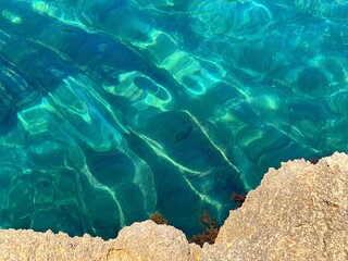 Sea blue turquoise water clear beautiful surface among coastal rocks.