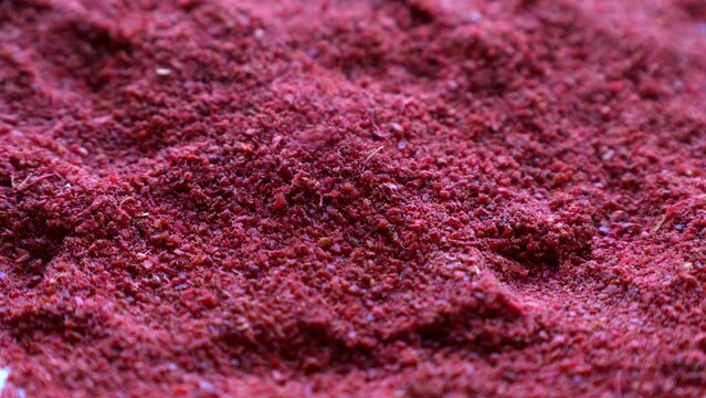Red sumac spice powder falling down close up