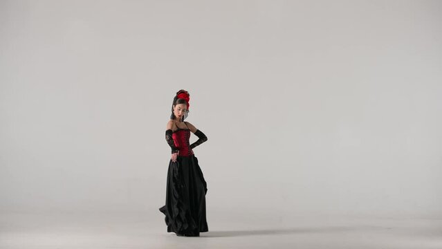 Woman dancer dancing on white background. Female in flamenco style dress performs elegant spanish dance moves with her hands and body in the studio.
