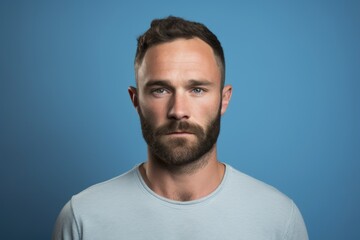 Portrait of a handsome young man with beard and mustache on blue background