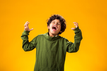 Angry child boy on yellow background. Negative children's emotions concept