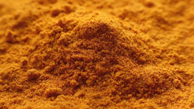 Ground yellow turmeric powder falling down close up