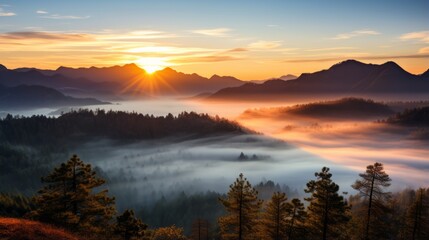 Fototapeta premium The sun is setting over a foggy mountain range