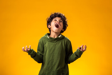 Angry child boy on yellow background. Negative children's emotions concept