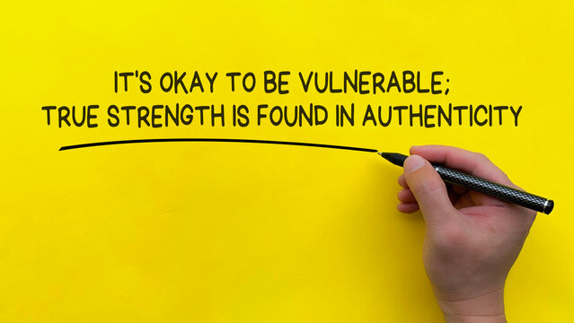 Hand writing It is okay to be vulnerable affirmation on yellow cover background. Affirmation concept.
