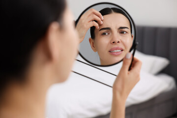 Woman with dry skin looking at mirror indoors
