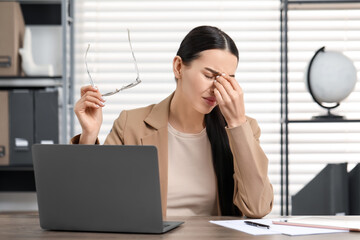 Woman suffering from headache at workplace in office