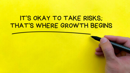 Hand writing It is okay to take risks affirmation on yellow cover background. Affirmation concept.