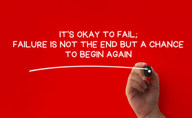 Hand writing It is okay to fail affirmation on red cover background. Affirmation concept.