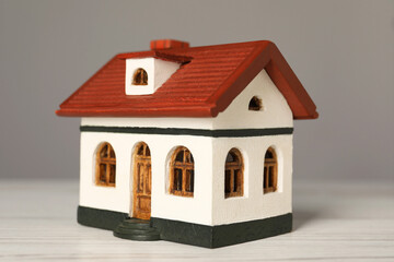 Mortgage concept. House model on white wooden table against grey background