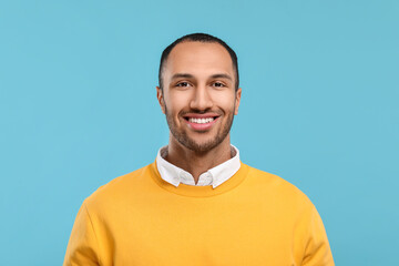 Portrait of smiling man with healthy clean teeth on light blue background