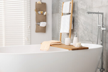 Set of different bath accessories and soap on tub in bathroom, space for text