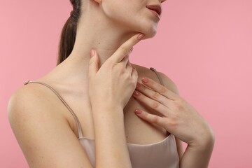 Obraz na płótnie Canvas Woman touching her neck on pink background, closeup