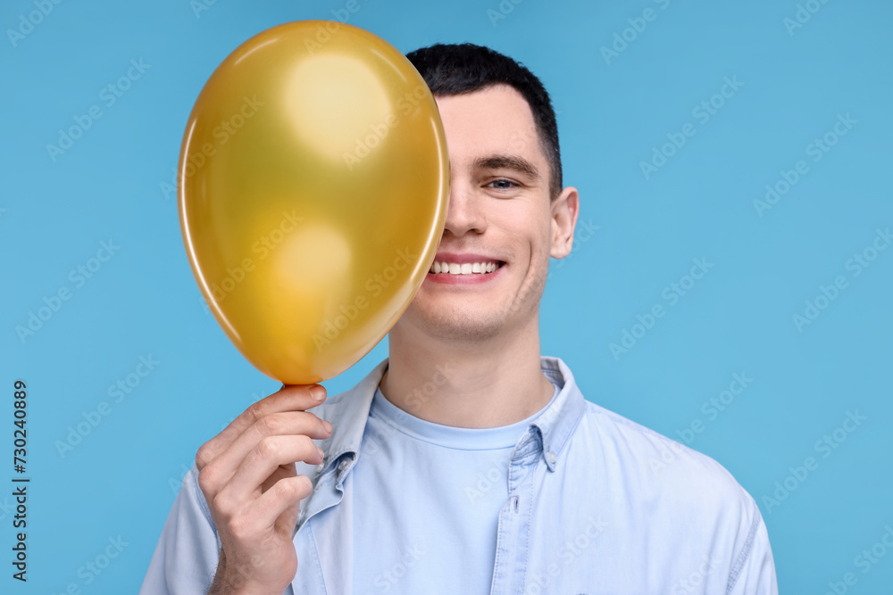 Canvas Prints Happy young man with golden balloon on light blue background