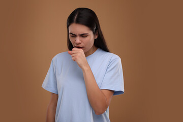 Woman coughing on brown background. Cold symptoms