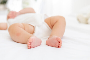 baby's small feet on a white bed, a place for text, a close-up of a little baby's feet