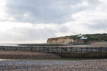Fototapeta premium Stunning chalk cliffs overlooking the beach, with Coastguard lodges on top overlooking the English Channel and the breathtaking natural beauty of the famous white cliffs under the shining sun
