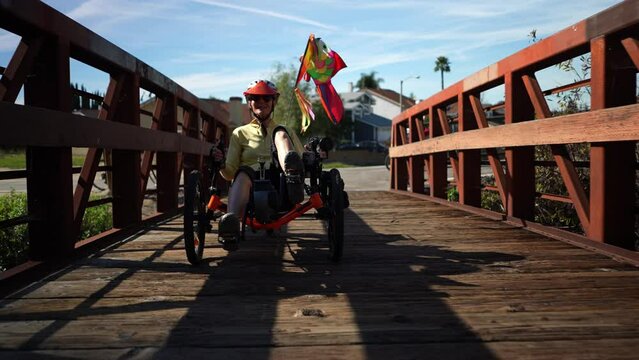 Elderly senior woman riding a recumbent electric bike over a bridge on a bike path in Southern California. Filmed in slow motion.