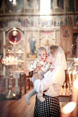 a mother with a small child in her arms in an Orthodox Christian church or temple prays or came to...